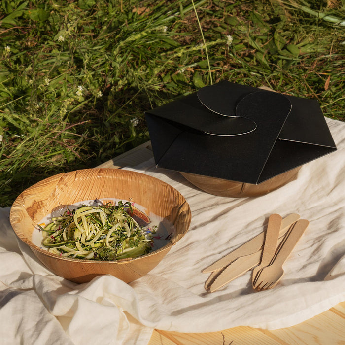 Zwei Take-Away Verpackung bei einem Picknick. Eine geschlossene und eine geöffnete Schale, gefüllt mit einem Gemüsegericht.